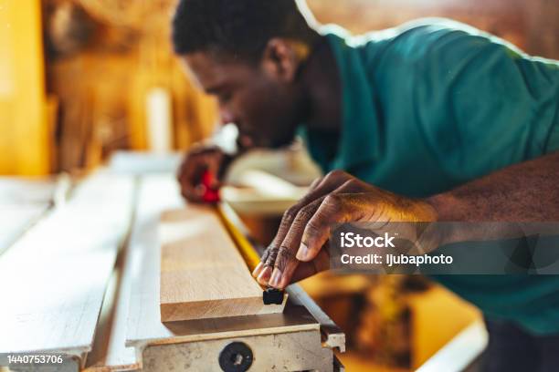 Close up detail of manual worker hands working with a measuring tape in wood plank