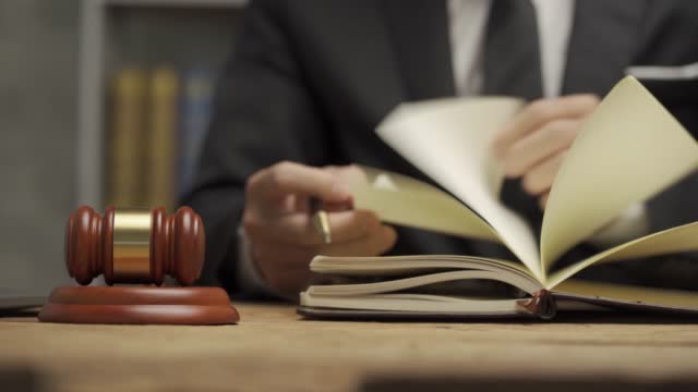 Young male lawyer working in the office Businessman or lawyer discussing laptop contract documents and judge's hammer with brass scales on table. 4k video.