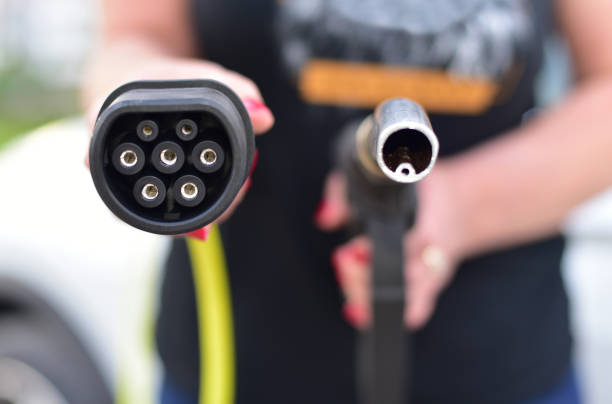 Fuel nozzle and electric car charger plug. EV vs gasoline. stock photo