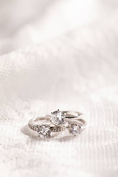 istock Vertical isolated closeup of diamond rings on a white lace background 1440761397
