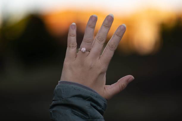 istock Female hand with engagement ring with blurry sunset in the background 1440761941