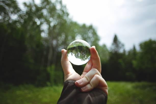 istock Person holding a crystal lens ball against a forest trees 1440762876