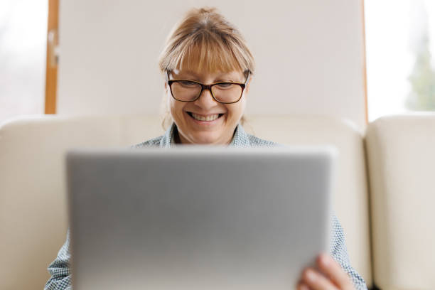 istock Active mature woman using a laptop for remote work from the home office. Video conference, video meeting. Senior teacher leads webinar 1440763091