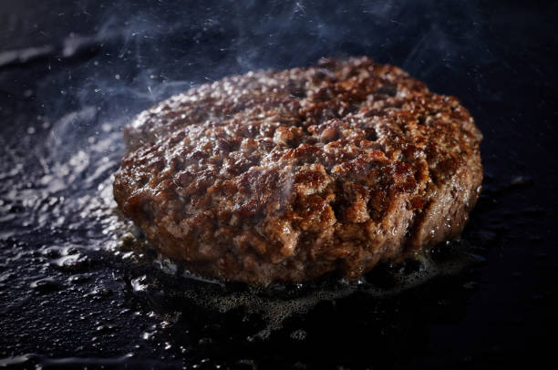 istock Thick juicy minced beef patty for a traditional burger grilling on a griddle 1440763165