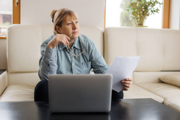 istock Active mature woman using a laptop for remote work from the home office. Video conference, video meeting. Senior teacher leads webinar 1440763198