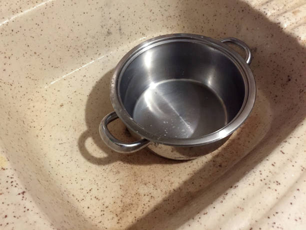 Dirty stainless steel saucepan in the kitchen sink