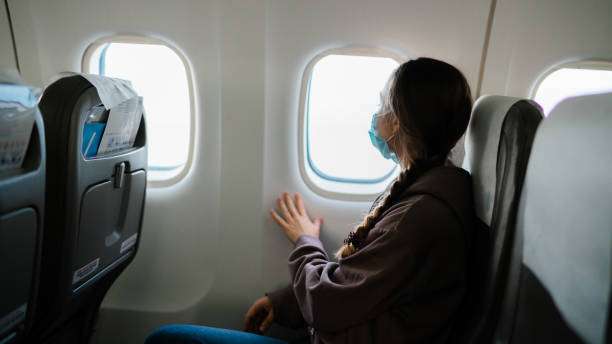 istock Young woman wearing face mask and looking outside the window during flight 1440764700