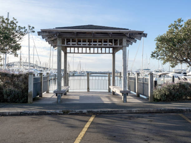 White gazebo at seashore with port with boats