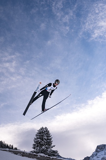 Kandersteg, Switzerland – December 17, 2021: A vertical shot of a competitor during the Ski jumping Contest in Kandersteg at Nordic Arena during Wintertime, Switzerland