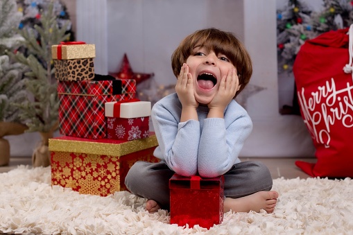A male child in Christmas mood put his hands on the face out of excitement, Christmas