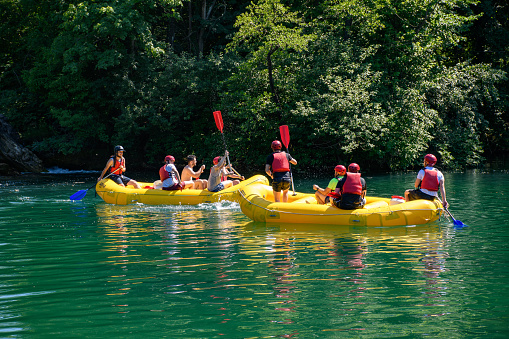 Duga Resa, Croatia – July 07, 2021: People in yellow whitewater raft having fun rafting on green river in summer. Mreznica river near Duga Resa in Croatia.