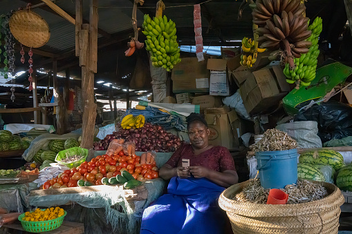 Havana, Cuba - August 15, 2022: A man standing beside a cart on a street corner. Bunches of avocados and other veggies are displayed on the cart.