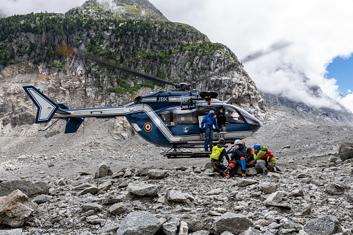 Chamonix, France – June 25, 2021: The rescuers of the french gendarmerie rescue an injured man by helicopter while hovering over the Mer de Glace glacier in Chamonix