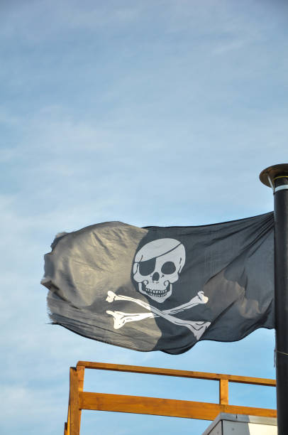 istock Black pirate flag swaying in the wind 1440768423