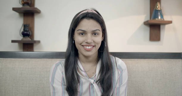 istock South Asian young female smiles brightly while sitting in the sofa 1440770592