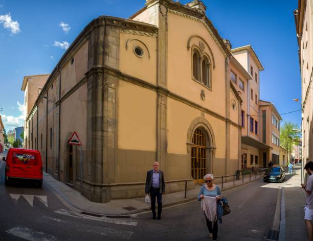 カタルーニャのオロト市、古い教会を背景に人と車が通り過ぎる通り。 - spain gerona architecture building exterior ストックフォトと画像