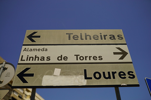 Lisbon, Portugal – July 13, 2021: A low-angle shot of a street sign to different destinations of Lisbon against a blue sky