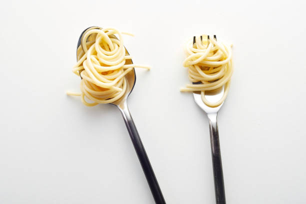 istock Top view of a fork and spoon with spaghetti in the white background 1440772103
