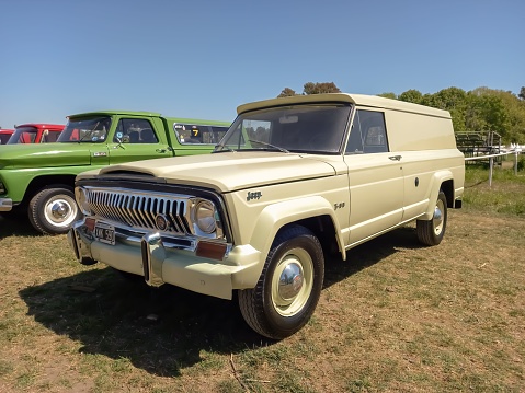 San Isidro, Argentina – October 08, 2022: old cream utility 1970 Jeep T-80 panel delivery van in a park. Sunny day. Autoclasica 2022 classic car show. Copyspace