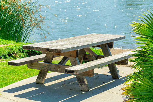 A wooden table with benches near the lake in a park