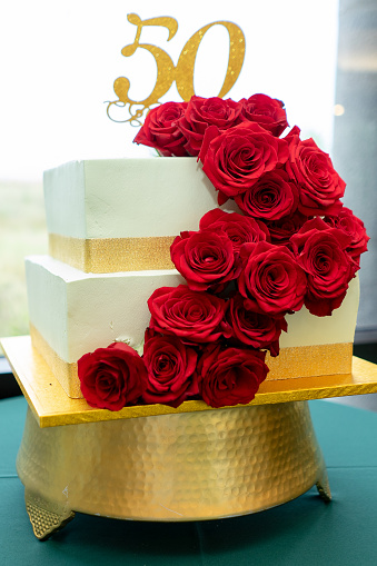 A vertical shot of a festivecake of 50th anniversary with red roses and golden strips