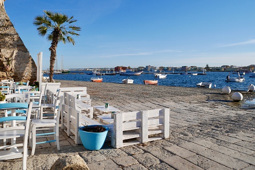 Lovely outdoor seating area with gorgeous view of the sea and fishing boats. Marzamemi, Province Syracuse, Sicily.