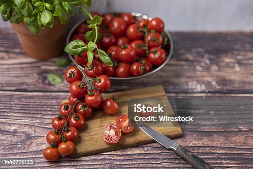 istock Some tomatoes on the vine upon a wooden cutting board with a kitchen knife. 1440776123