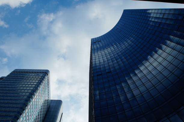 Old skyscrapers meet newer ones. The 'Silberturm' (silver tower) and Skyper compete to reach the sky in Frankfurt. Reflecting a blue-white sky.