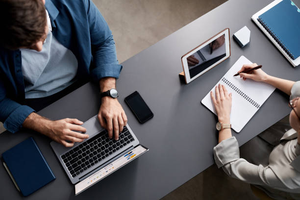 Above view of young coworkers using mobile gadgets during individual work