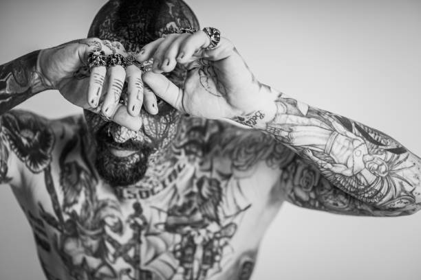 grayscale shot of a cool caucasian man with his whole body and face covered with tattoos - men sex symbol sensuality human face imagens e fotografias de stock