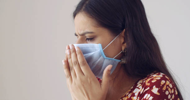 istock Young Indian with a mask coughing on a white wall background 1440778656