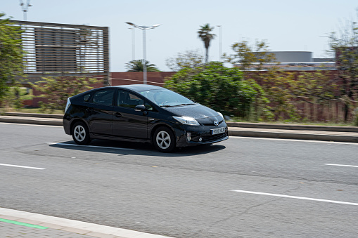 Barcelona, Spain – June 18, 2021: Panning of hybrid car in the city. It's a black Toyota Prius