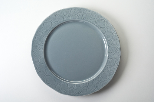 A top view of a gray plate with pretty ornament on edges on white background