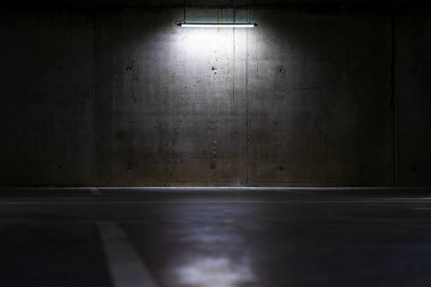 istock Empty parking lot with overhead dim light, underground parking garage. 1440781857