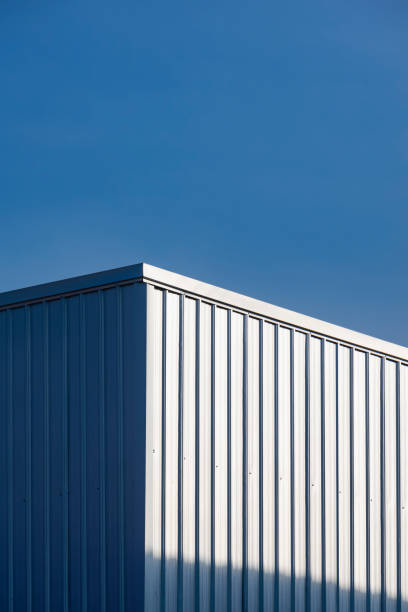istock Corrugated steel warehouse building wall with sunlight reflection on surface against blue clear sky background 1440782006