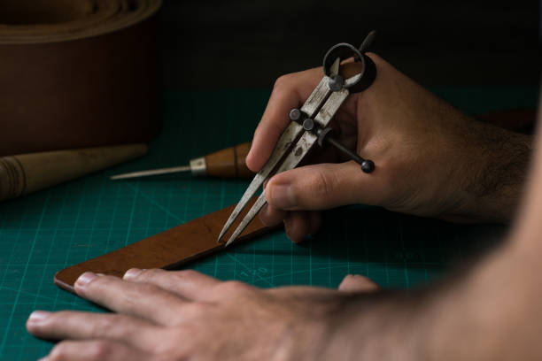 istock Closeup of a man's hands working with a tool for leather crafting. 1440783439