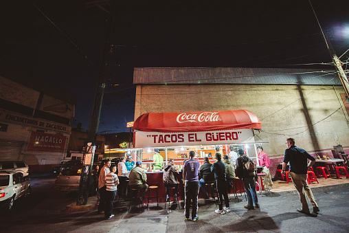 Zacatecas, Mexico – April 01, 2018: A group of people waiting in line and other people eating at a Mexican street food stall at night in Zacatecas, Mexico