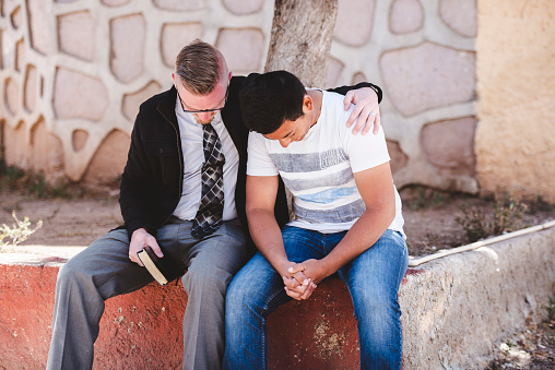 Zacatecas, Mexico – April 01, 2018: An American missionary talking to and praying with a Mexican male