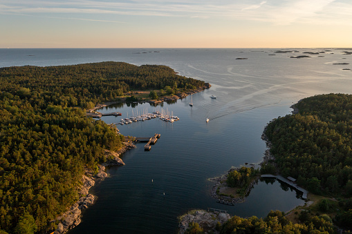 Aerial drone view of a boat arriving to a guest harbor at the Jussaro island, summer evening, in the finnish archipelago