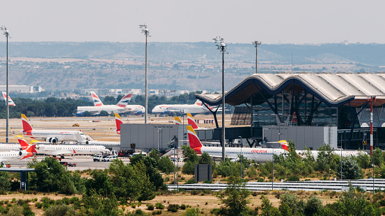 Madrid, Spain – June 26, 2021: Madrid Bajaras, June 26, 2021: Long zoom view of airplanes on tarmac and iconic roof of Bajaras Airport in Madrid, Spain