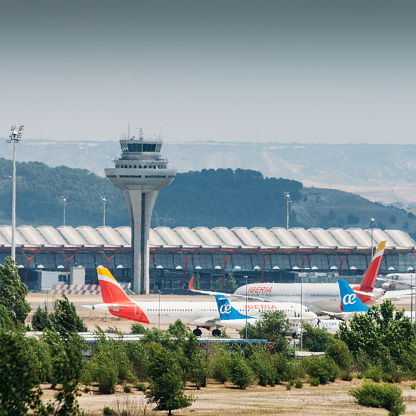 Madrid, Spain – June 26, 2021: Madrid Bajaras, June 26, 2021: Long zoom view of airplanes on tarmac and iconic roof of Bajaras Airport in Madrid, Spain