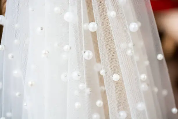 Photo of Closeup shot of a bride veil enveloped in pearls