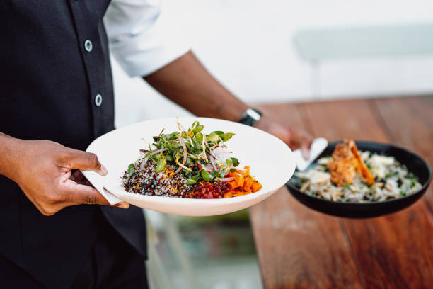 istock Midsection of a waiter serving two dishes on a wooden table 1440784721