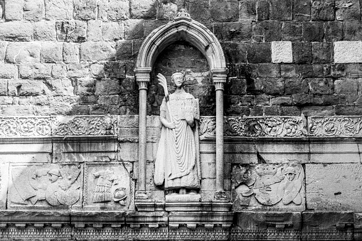 A grayscale of Romanesque-Byzantine statue of San Giusto on the bell tower of Saint Justus cathedral