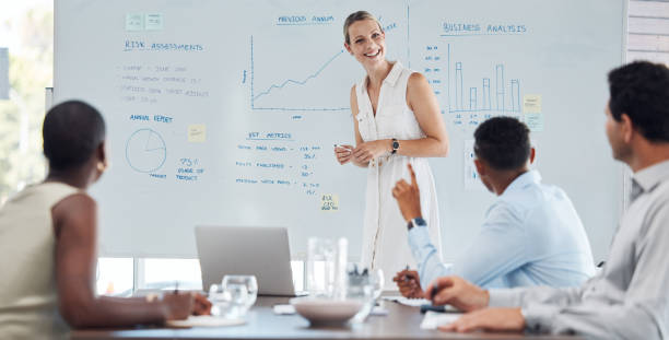 istock Presentation, training and data with a female leader, manager or CEO and her team in a meeting for strategy and planning. Collaboration and teamwork during a seminar or workshop for development 1440788135