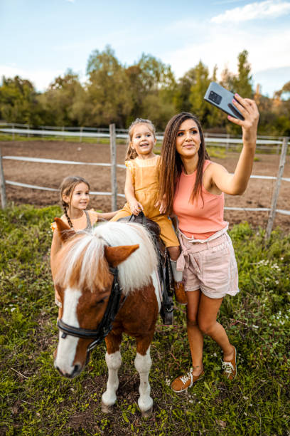 말 목장에서 셀카를 찍는 두 어린 딸을 둔 어머니 - teaching child horseback riding horse 뉴스 사진 이미지