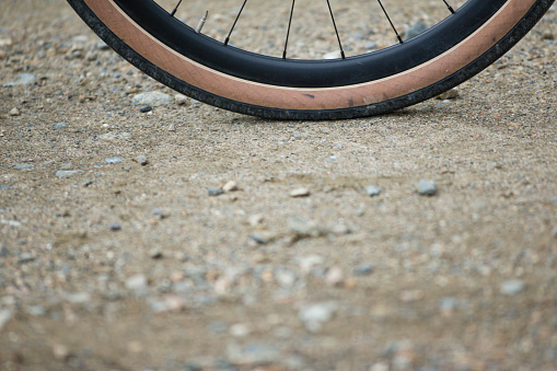 A close-up view of the wheel and tire of a gravel bicycle. Gravel bicycles are similar to road bikes but with oversized tires for riding on rough terrain.