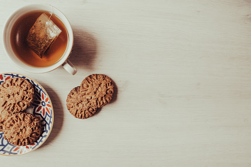 Homemade biscuits and cup of tea on white wooden table - Copy space