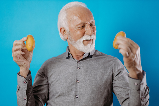 Senior man holding vegetables, promoting healthy eating
