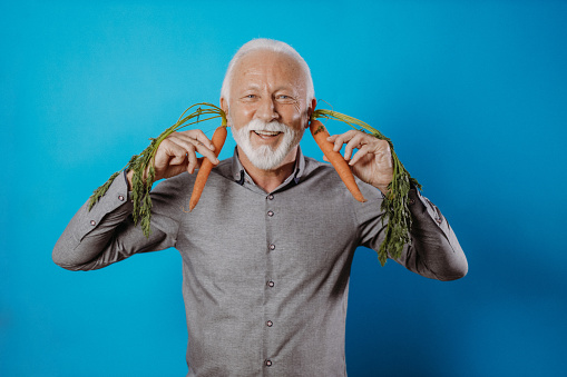 Senior man holding vegetables, promoting healthy eating